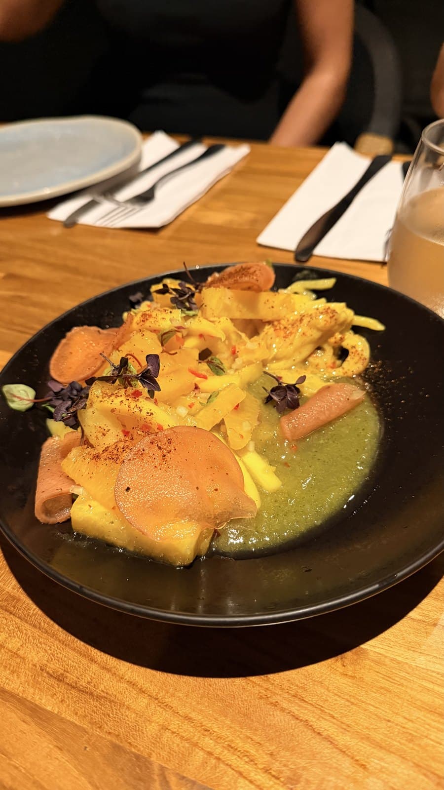 The pineapple and mango salad at Cantina del Tigre, shaved fruit with micro herbs and chilli over a green herb sauce in a black bowl