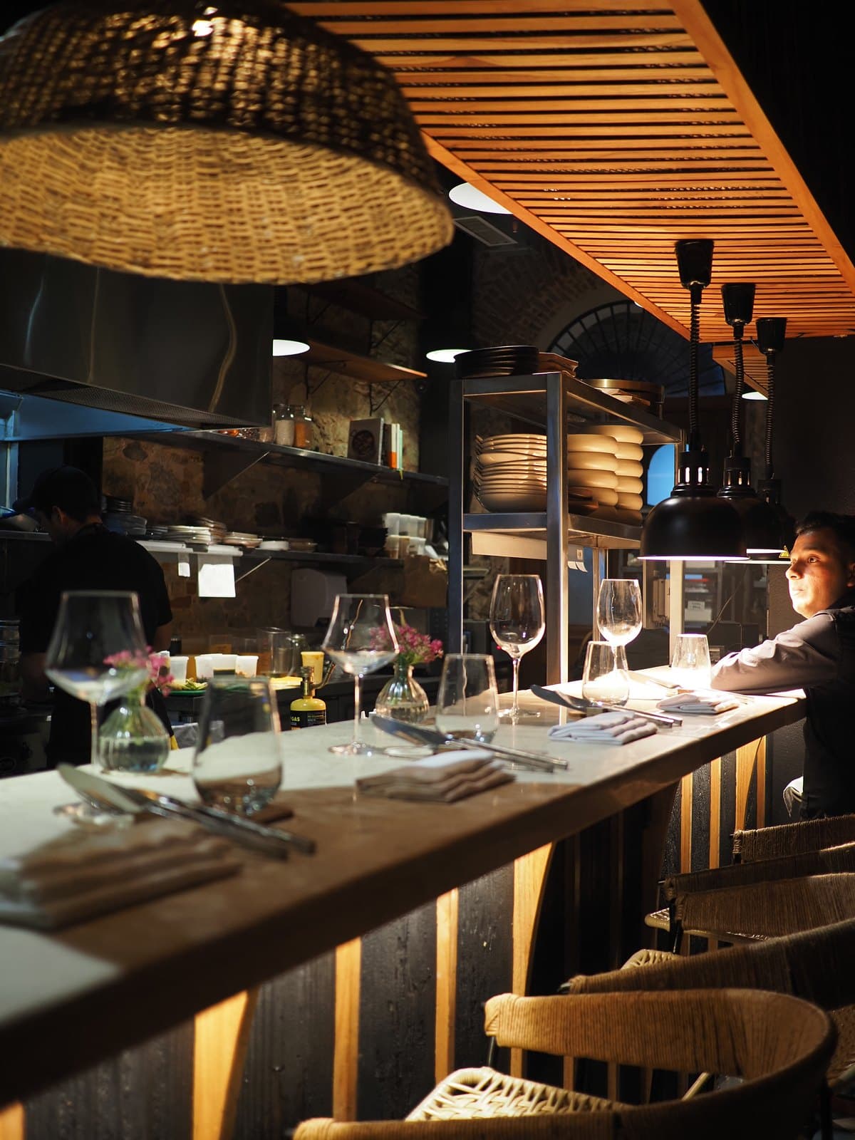 The dining room at Kaandela, Casco Viejo: woven pendant lamps over a long counter with tables set for service