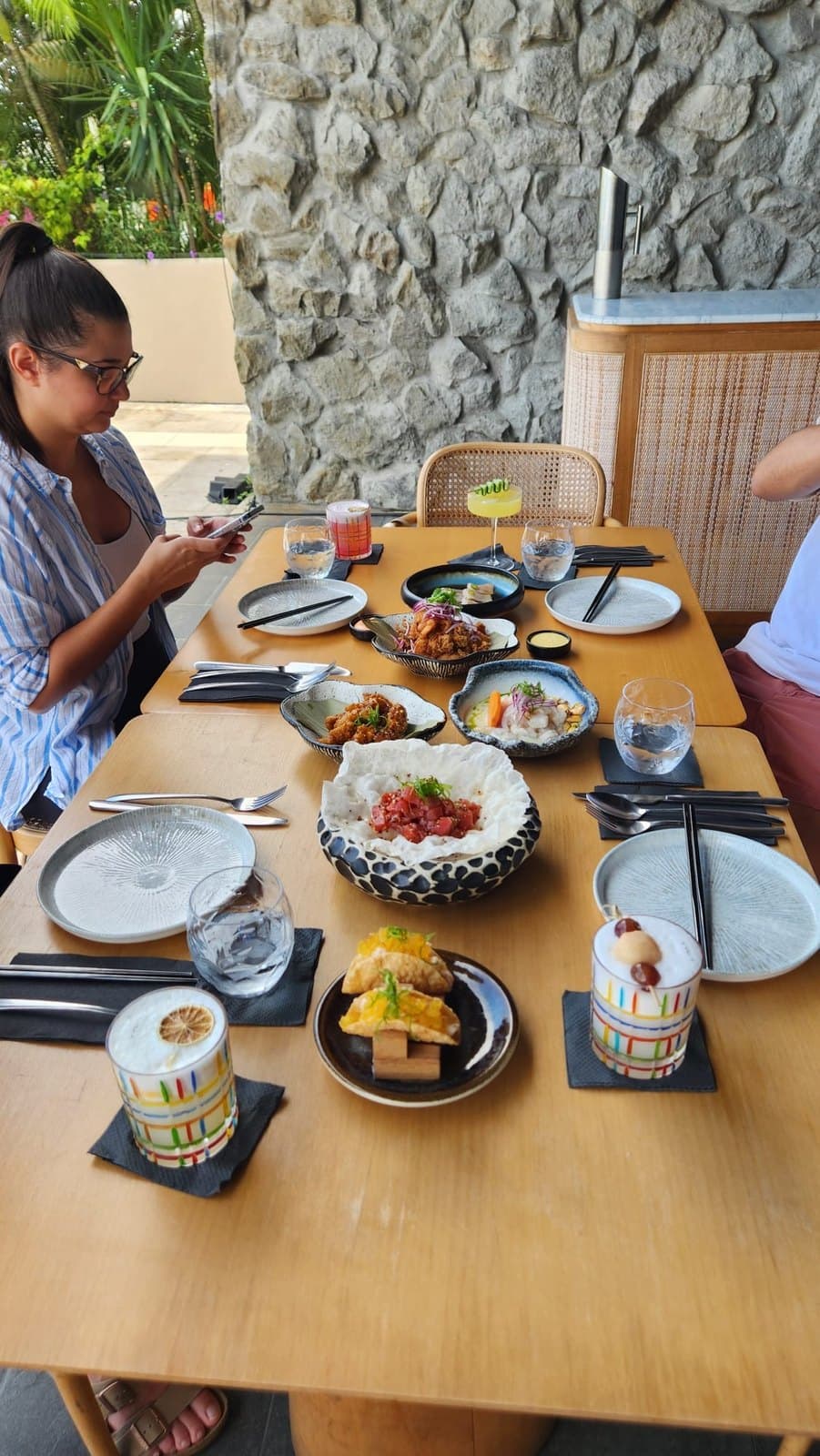 A long table laid for lunch on the terrace at Lima Nikkei, against a stone wall