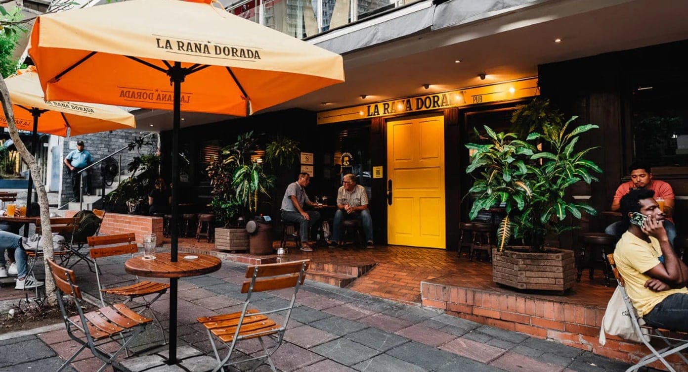 Open-air sidewalk terrace with orange umbrellas and patio tables at La Rana Dorada, Vía Argentina, Bella Vista, Panama City