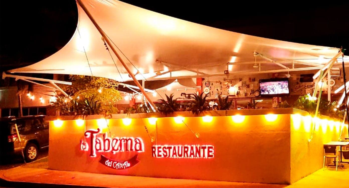 Patio al aire libre con toldo blanco y luces colgantes en La Taberna del Canal, Clayton, Ciudad de Panamá