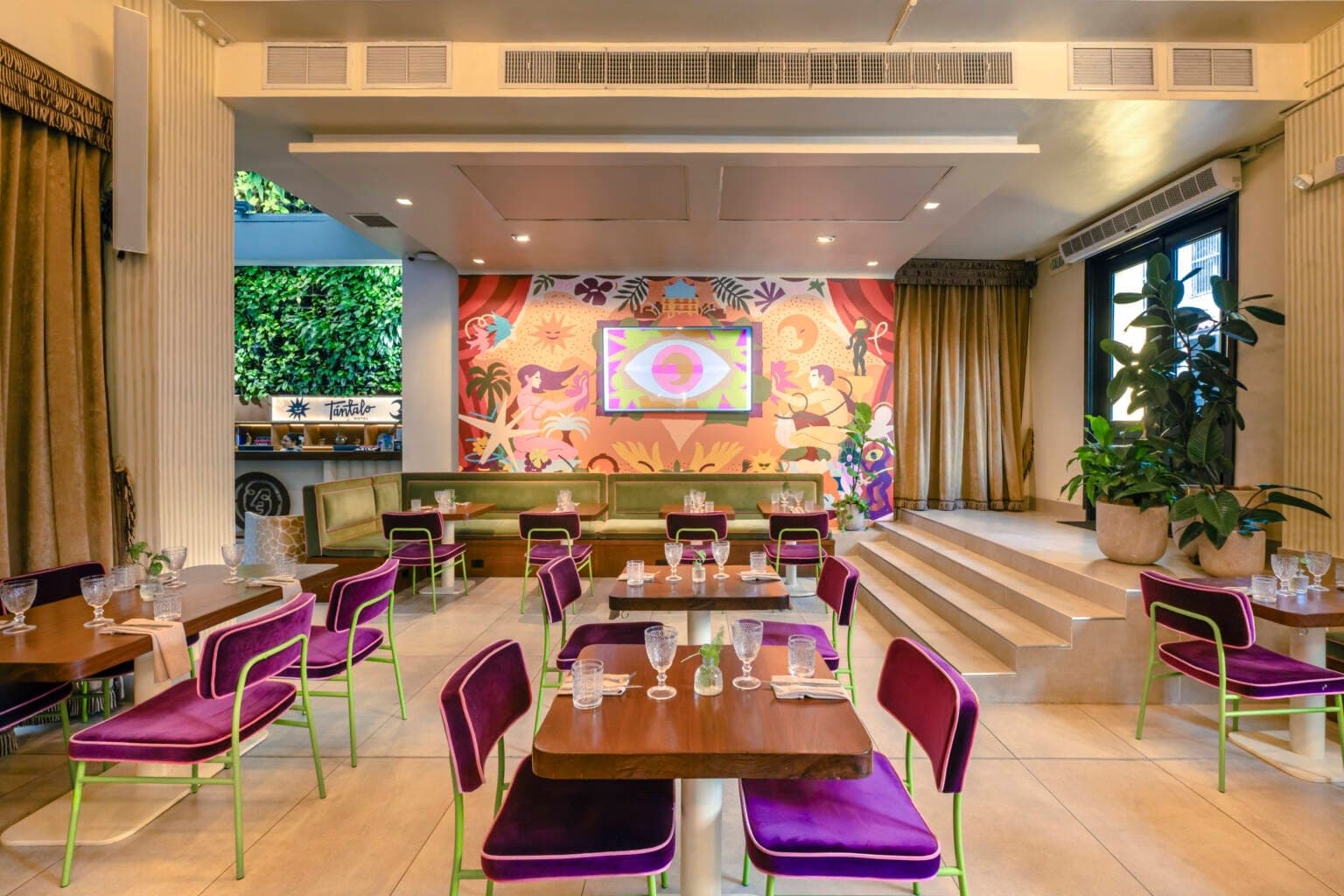 Comedor interior con sillas de terciopelo morado y muro verde en Alura, Casco Viejo, Ciudad de Panamá