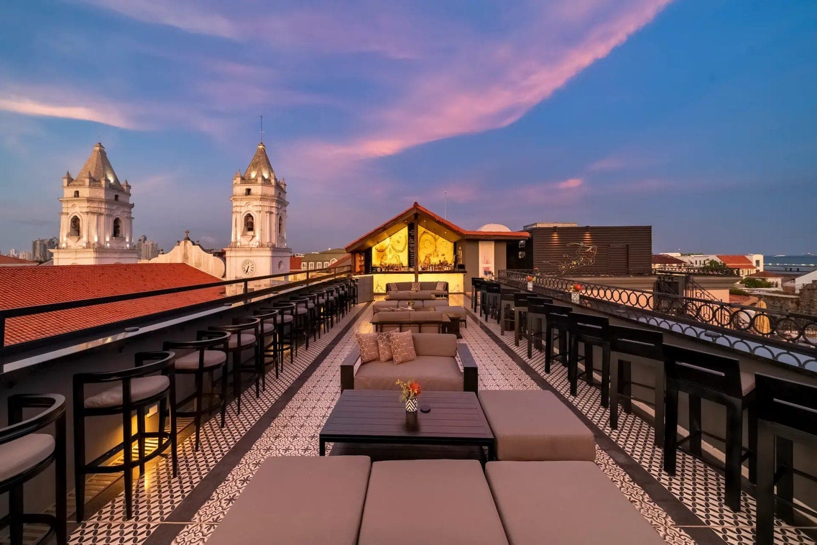 Rooftop lounge deck at dusk with the cathedral towers and Panama City skyline at Capella Rooftop, Casco Viejo