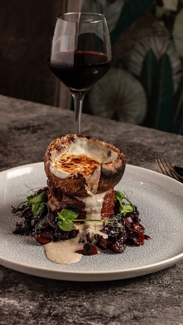 Carne coronada con portobello relleno gratinado y una copa de vino tinto en Centrico Atypical Steakhouse, Bella Vista, Ciudad de Panama