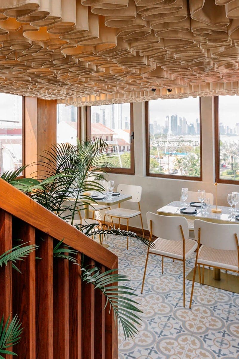 Rooftop dining room with a wood-slat ceiling and the Panama City skyline through the windows at Lazotea, Casco Viejo