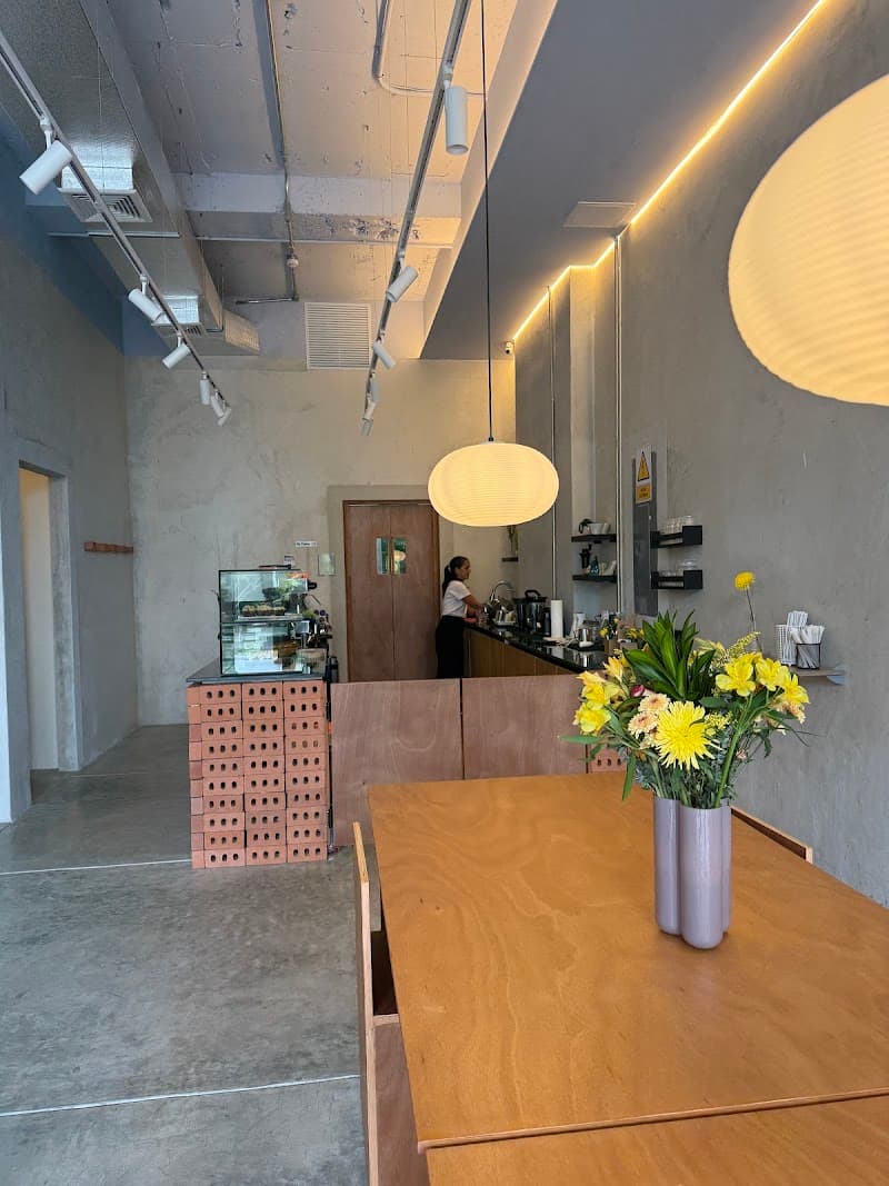 Raw concrete walls, a single paper lantern and a long communal wood table - built for lingering, not a quick takeaway.