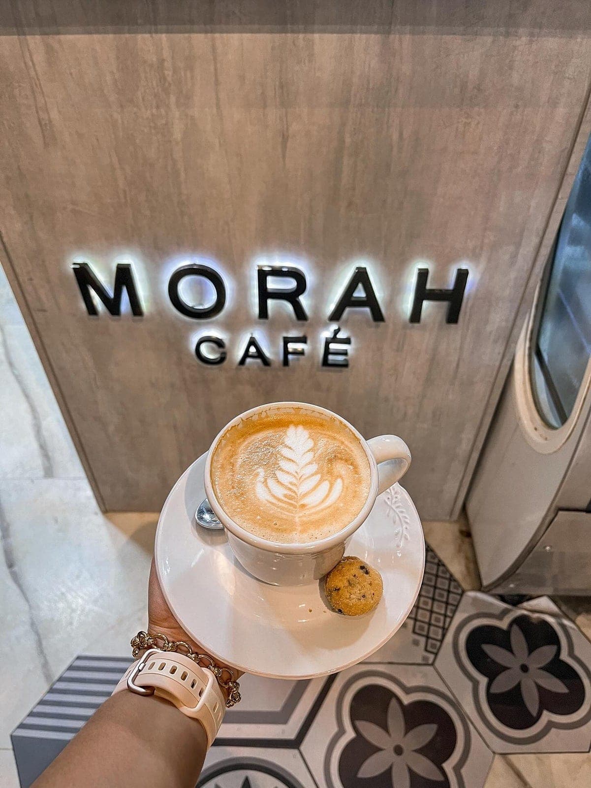 Latte with rosetta art against the branded interior wall at Morah Café, Casco Viejo, Panama City